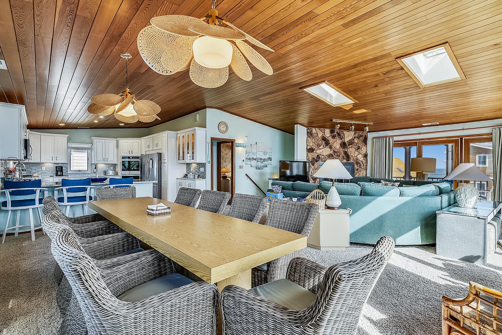 Sunlight pours through skylights onto a spacious open floor plan where you'll gather around the dining table, cook in the fully equipped kitchen, and unwind on plush seating with gorgeous views beyond.