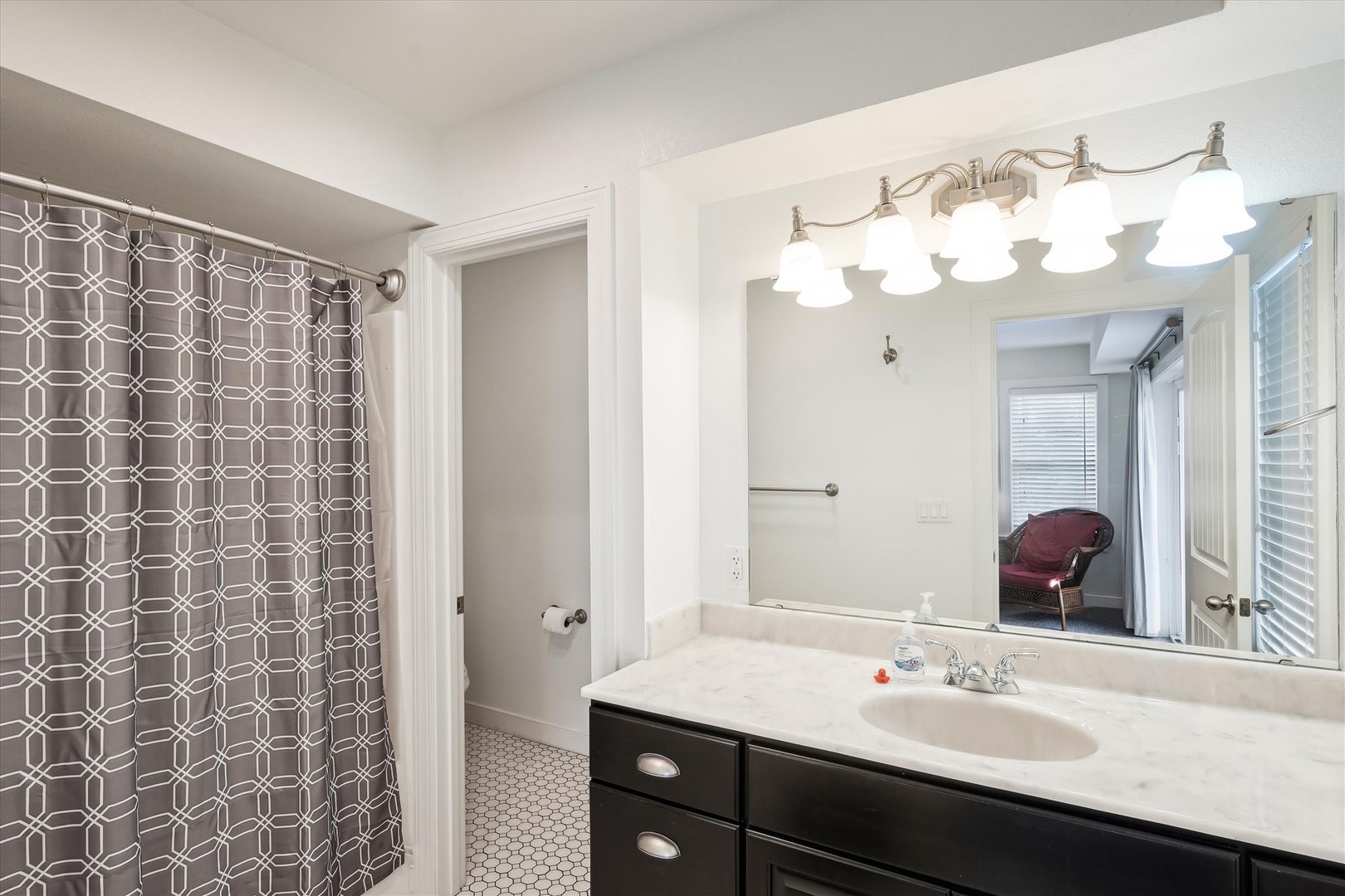 Your bright, updated bathroom features a spa-like vanity with elegant lighting, a spacious walk-in shower with stylish curtain, and plenty of counter space to spread out as you prepare for the day.