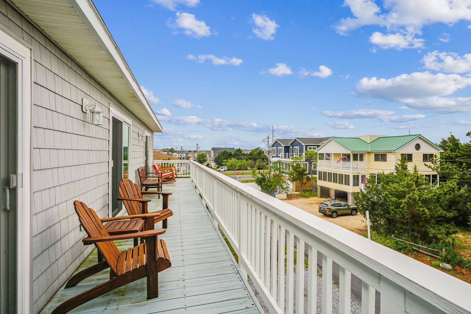 This upper-level balcony offers a welcoming spot with classic Adirondack chairs, where you can relax and take in the views of the surrounding coastal neighborhood.