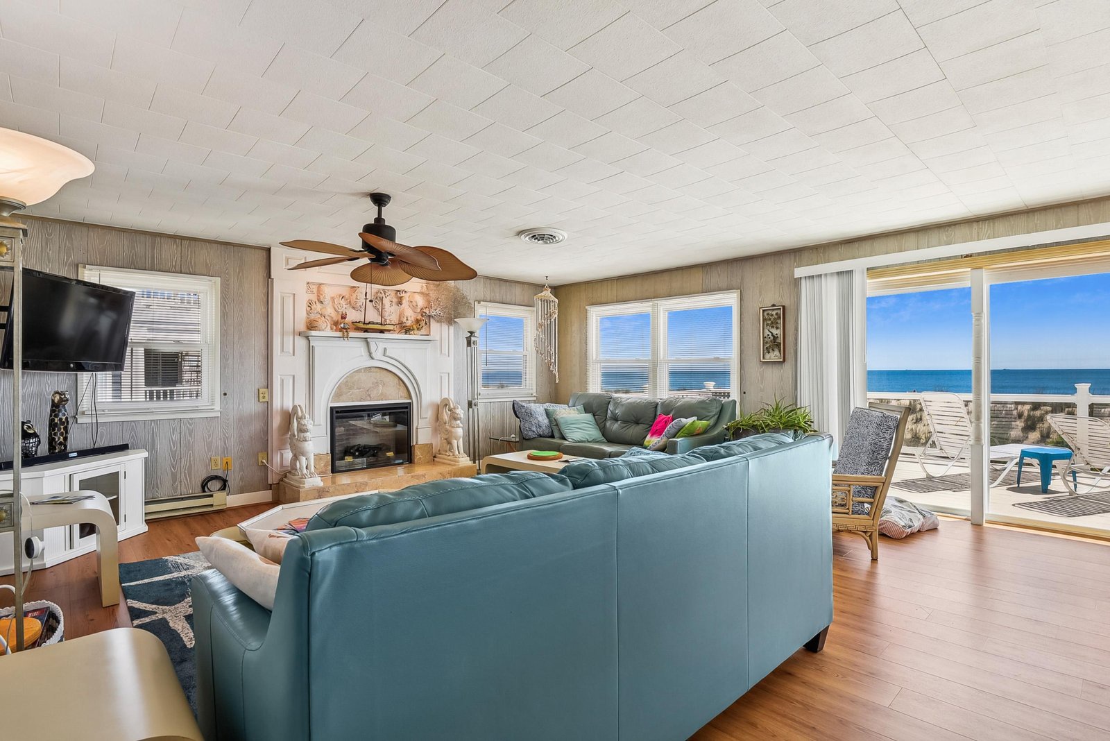 Sink into plush seating while sunlight and sweeping ocean views pour through floor-to-ceiling windows, creating your perfect beachside retreat with cozy fireplace ambiance.
