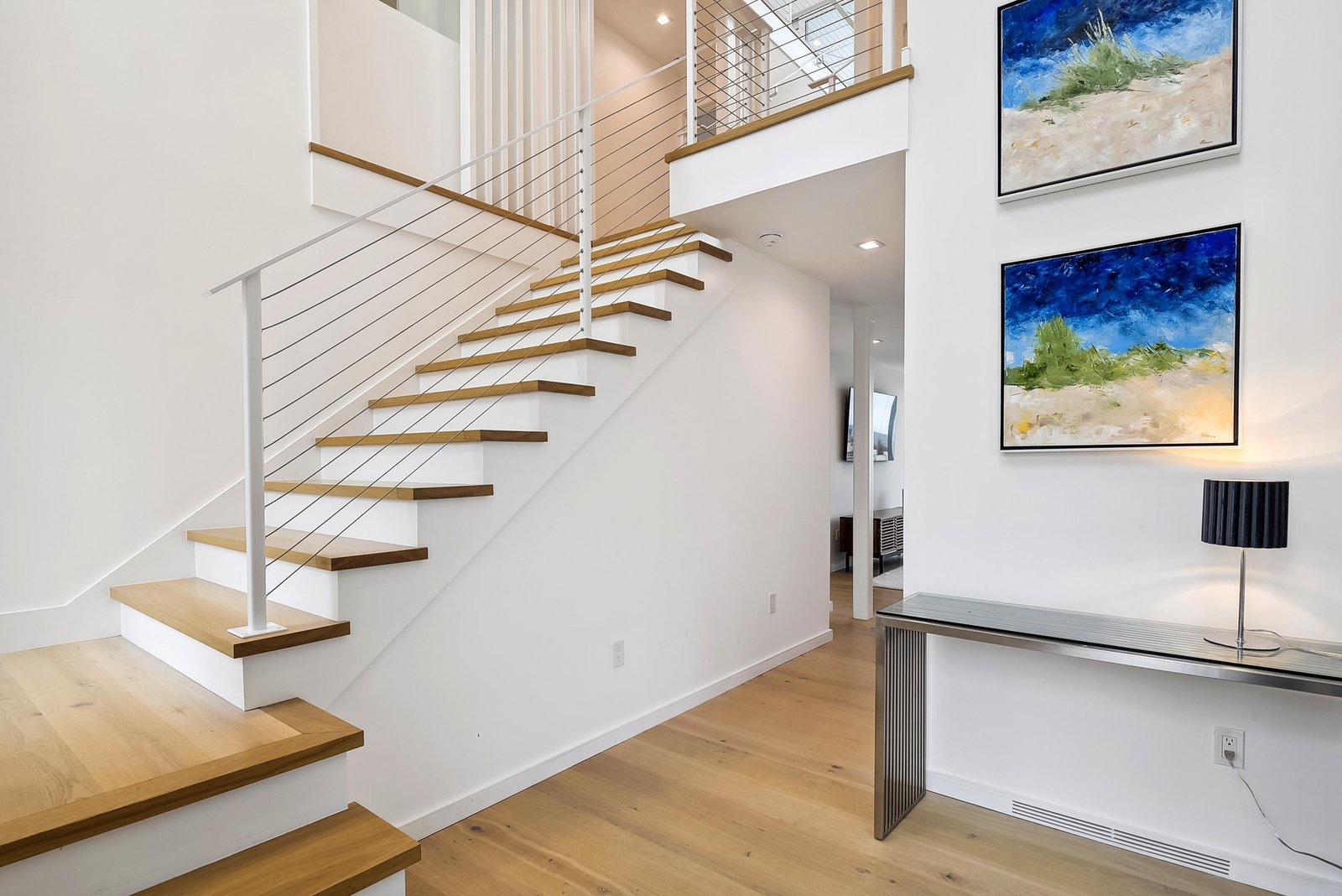 Step inside to find a bright, open staircase with sleek wood treads and modern cable railing, welcoming you to explore your stylish retreat.