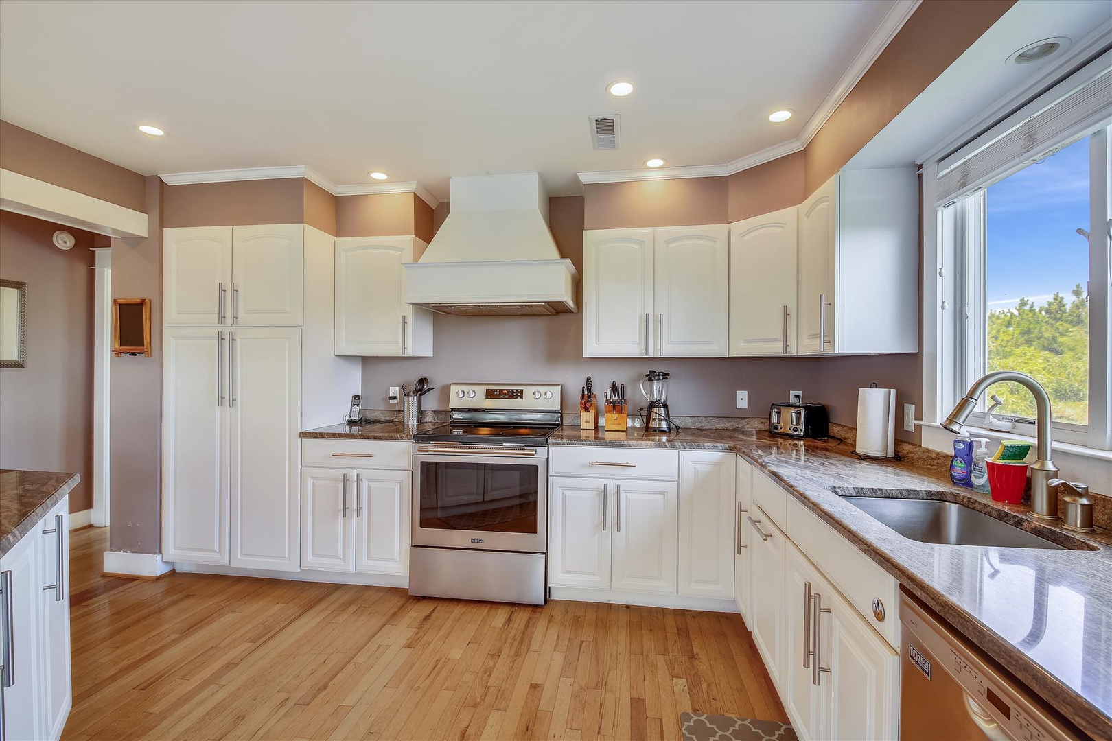 Prepare delicious meals in this bright, fully equipped kitchen featuring modern appliances, ample counter space, and warm natural light streaming through the windows.