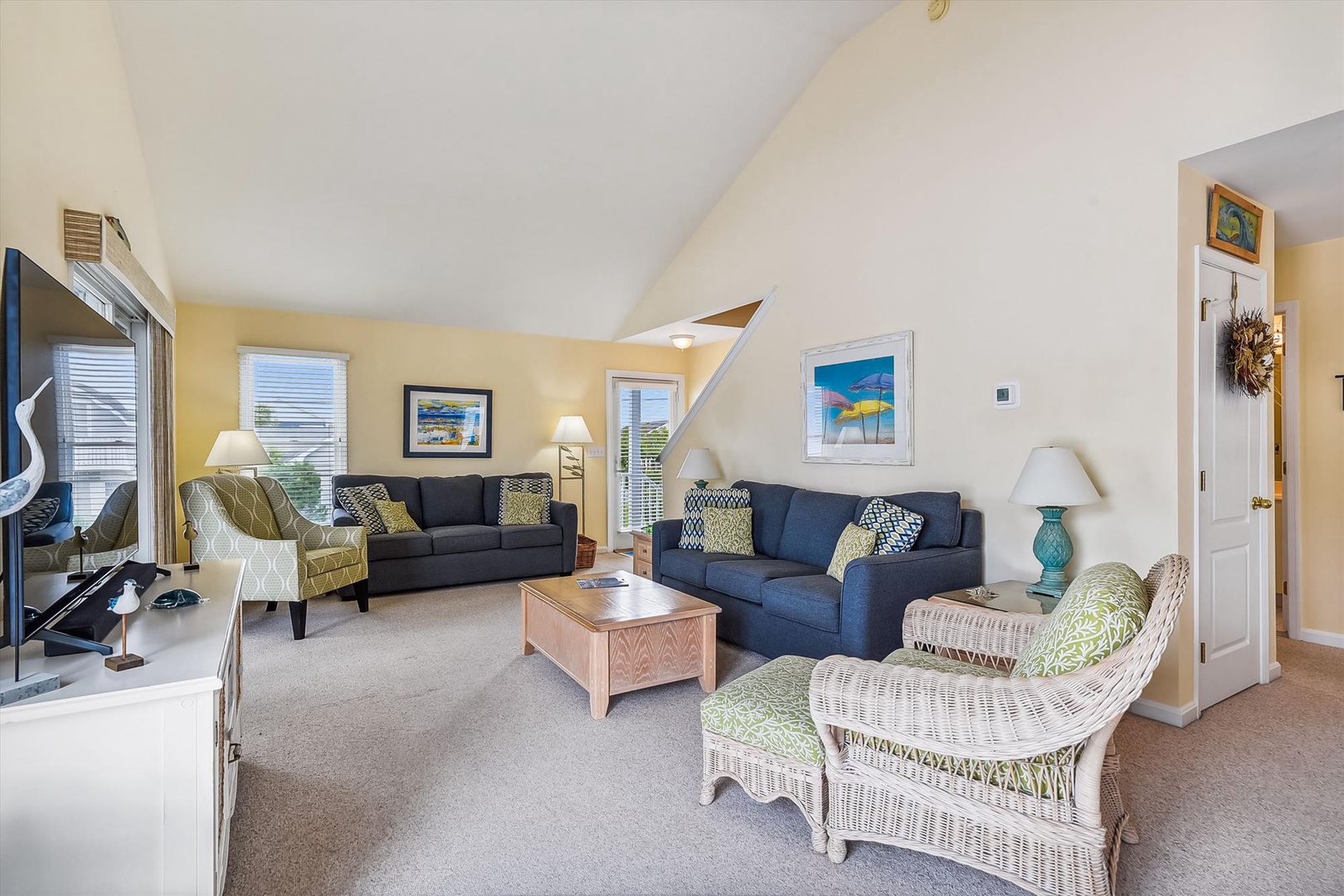Your bright coastal living room awaits with comfy sofas, beachy décor, and vaulted ceilings perfect for unwinding after a sun-soaked day.
