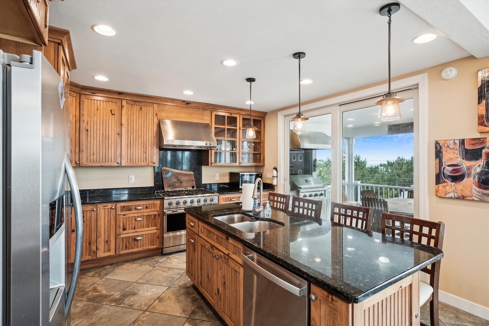 Your chef-ready kitchen features gleaming granite counters, stainless appliances, and pendant lighting—all opening to a sunlit dining area with peaceful forest views through expansive windows.