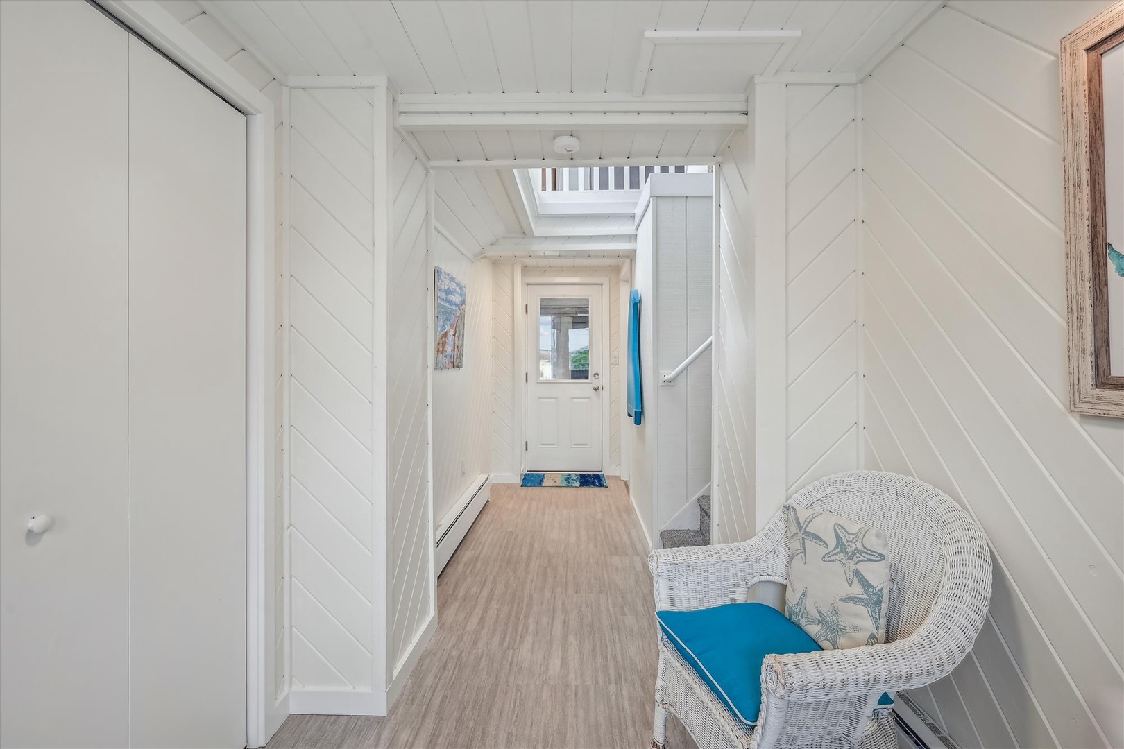 Bright, coastal-themed entryway welcomes you with whitewashed wood walls, charming skylights, and coastal décor—setting a relaxed, beachy tone from the moment you step inside.