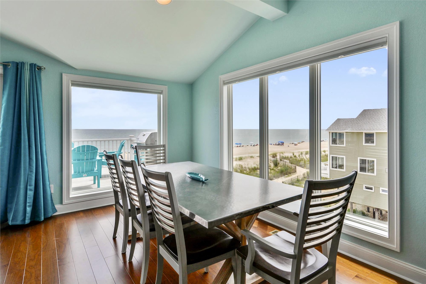 Enjoy meals with stunning ocean views through expansive windows that frame the beach and coastline, creating a perfect dining experience in this bright, coastal-inspired space.