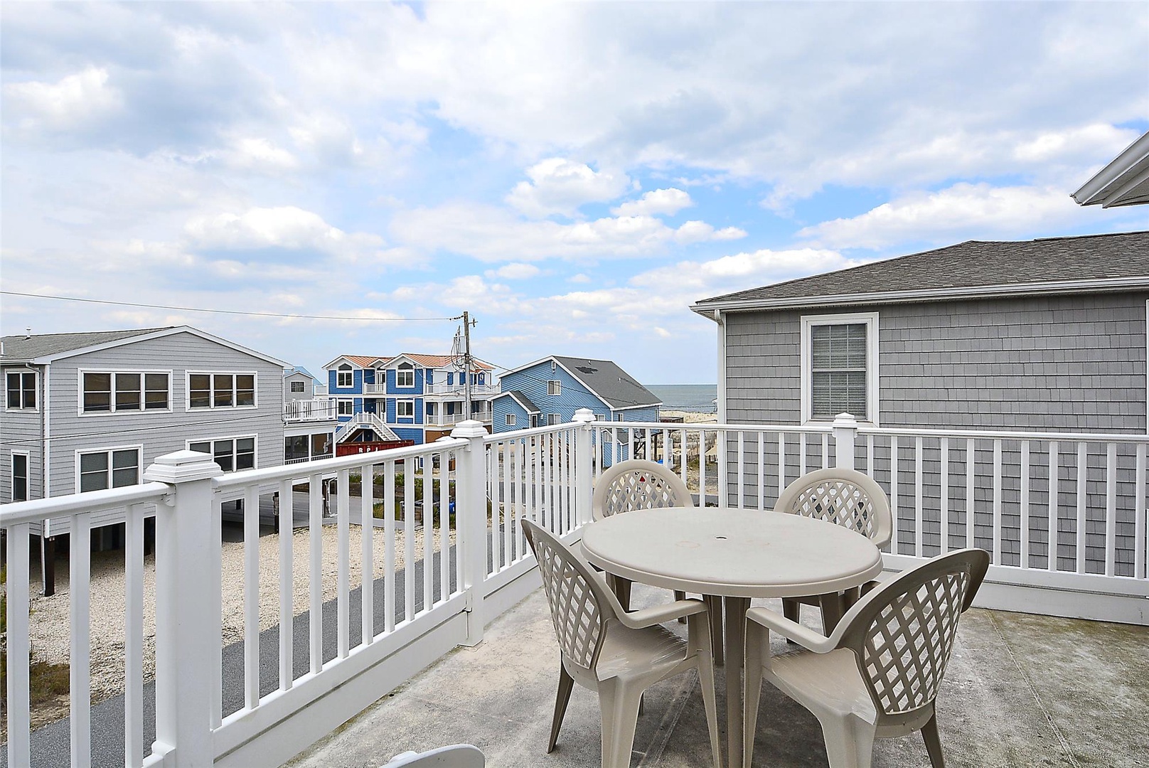 This elevated deck features a small dining set perfect for morning coffee or evening meals while taking in views of the coastal neighborhood and glimpse of water beyond.