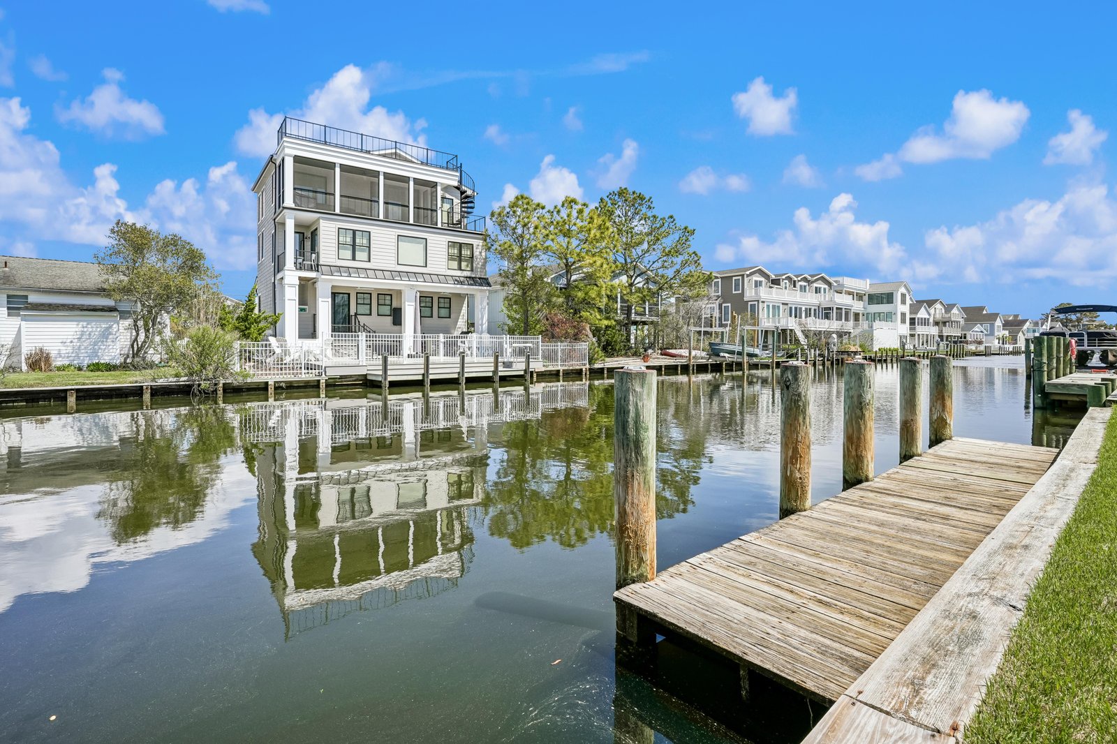 Modern waterfront property situated on a serene canal with private docking facilities. The building features a rooftop deck and is surrounded by a peaceful residential neighborhood with mature trees.