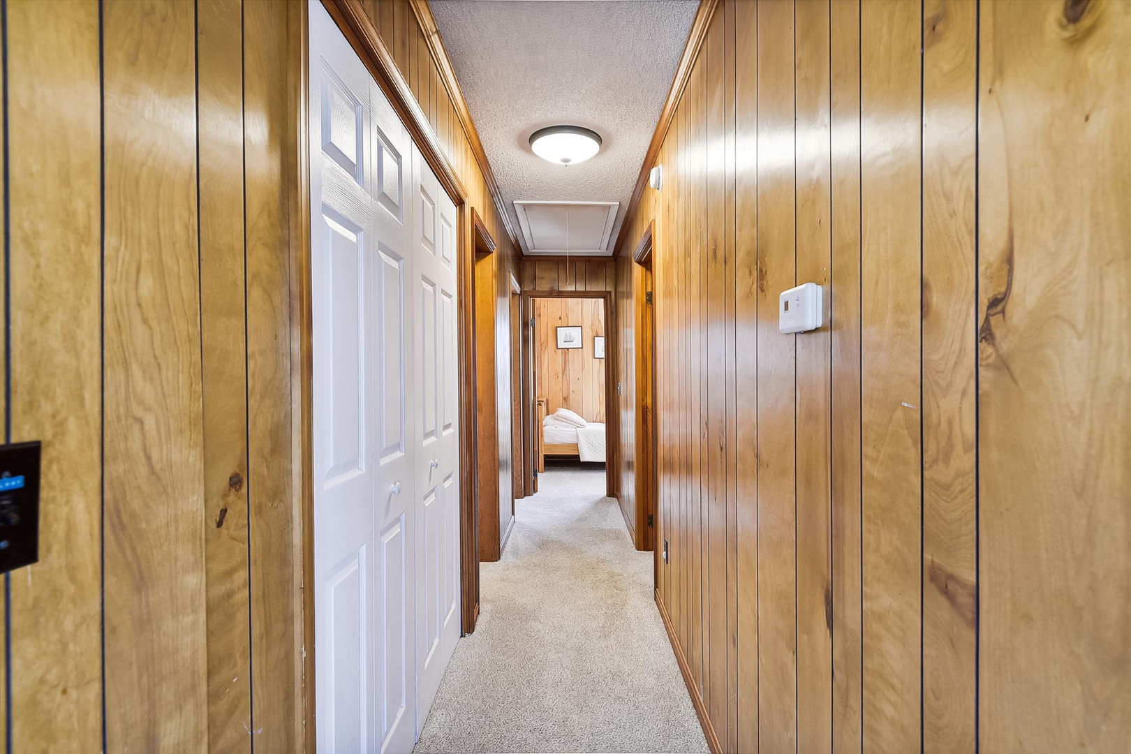 A welcoming hallway with warm wood paneling connects the spaces, leading you from room to room with cozy, homey charm and soft carpeting underfoot.