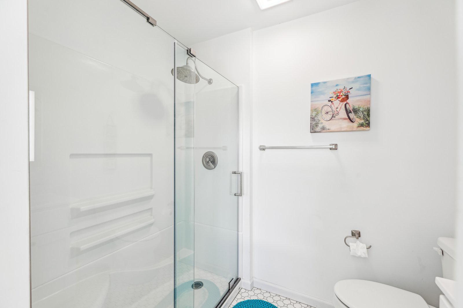 Step into your sparkling clean private bathroom, where bright white tiles and a modern glass-enclosed shower await. Fresh towels and thoughtful touches create a spa-like retreat after your adventures.