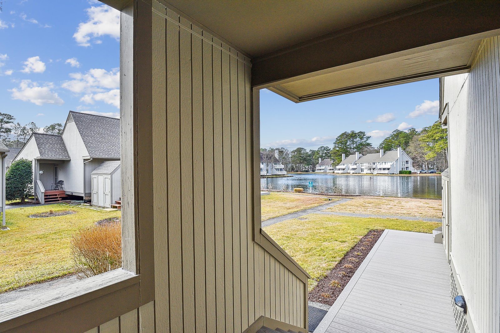 A peaceful water view awaits from your private screened porch, overlooking a tranquil lake, lush green lawns, and the serene community beyond.