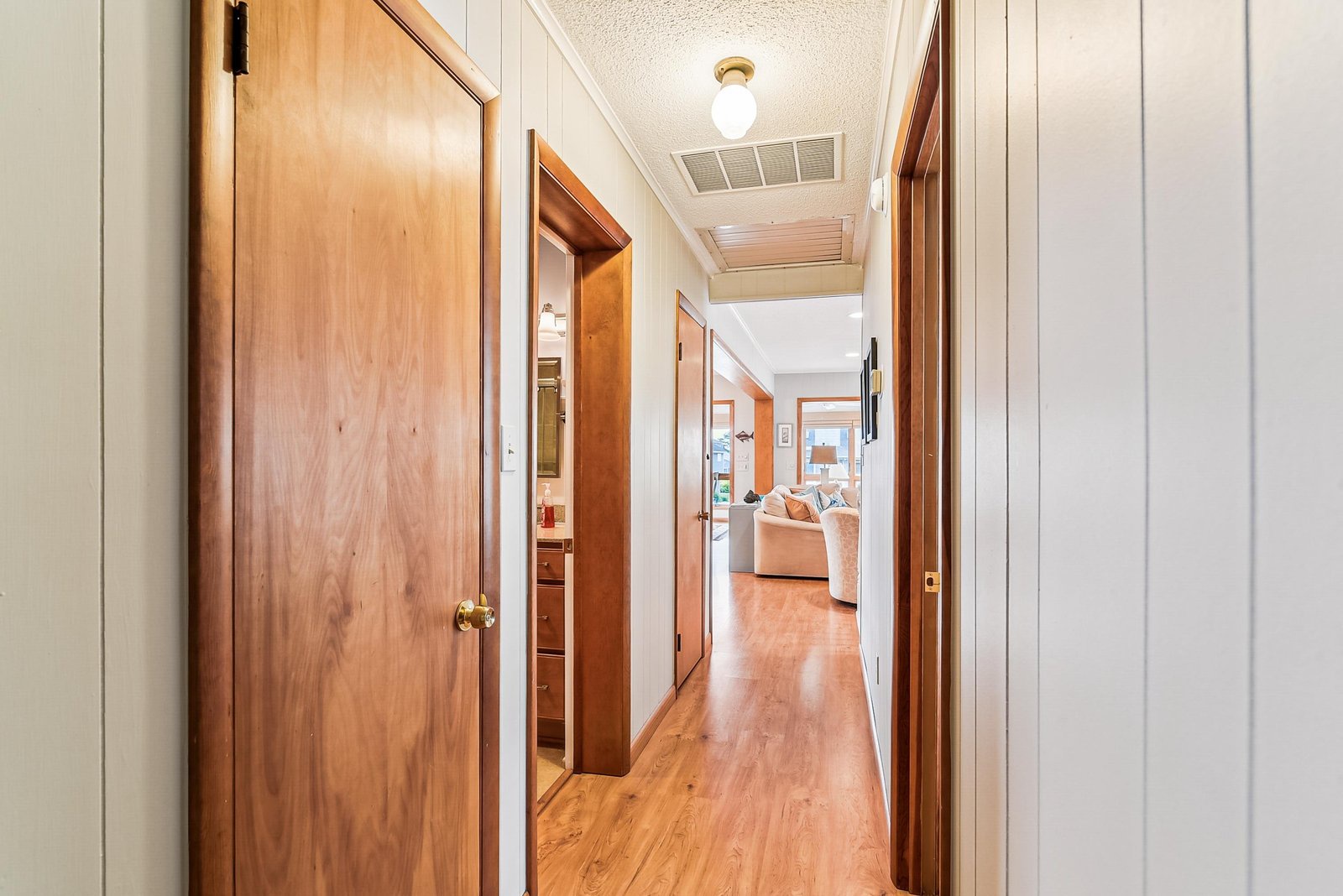This bright hallway connects your private spaces to the inviting living area, with warm wood floors underfoot and plenty of natural light to guide your way.