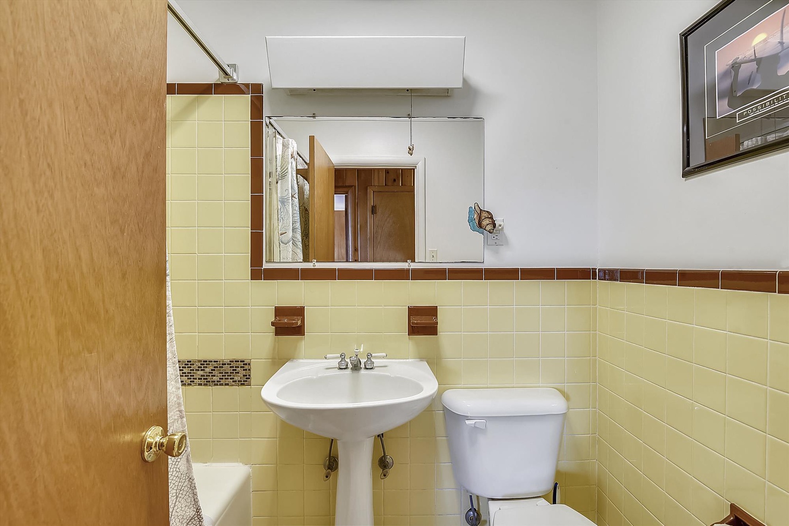 Your private bathroom features classic tilework with a pedestal sink, toilet, and storage cabinet—everything you need for a comfortable stay.