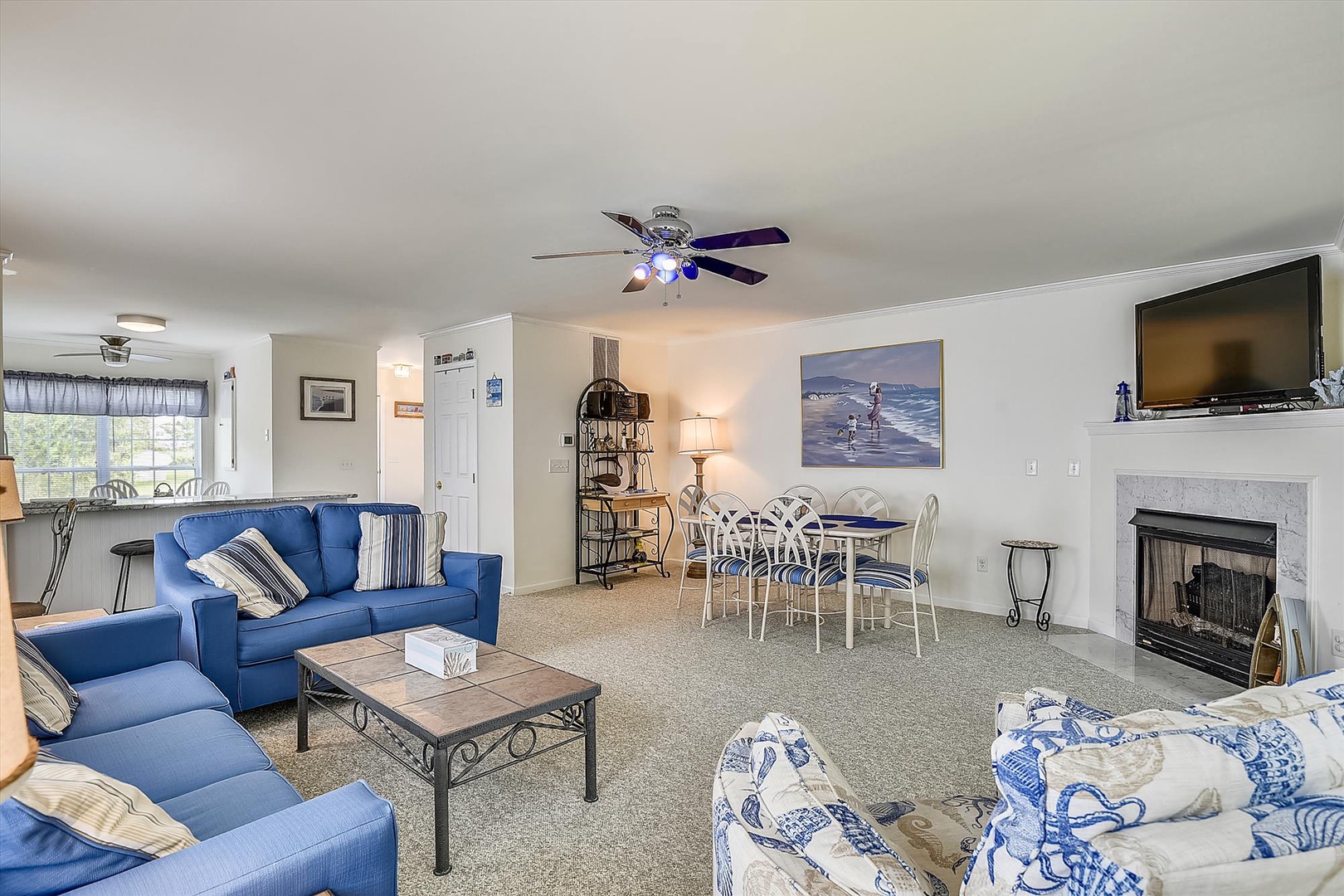 Unwind in this bright, open living space with coastal blue seating, a cozy fireplace, and ocean-inspired art. Perfect for relaxing evenings or gathering with loved ones.