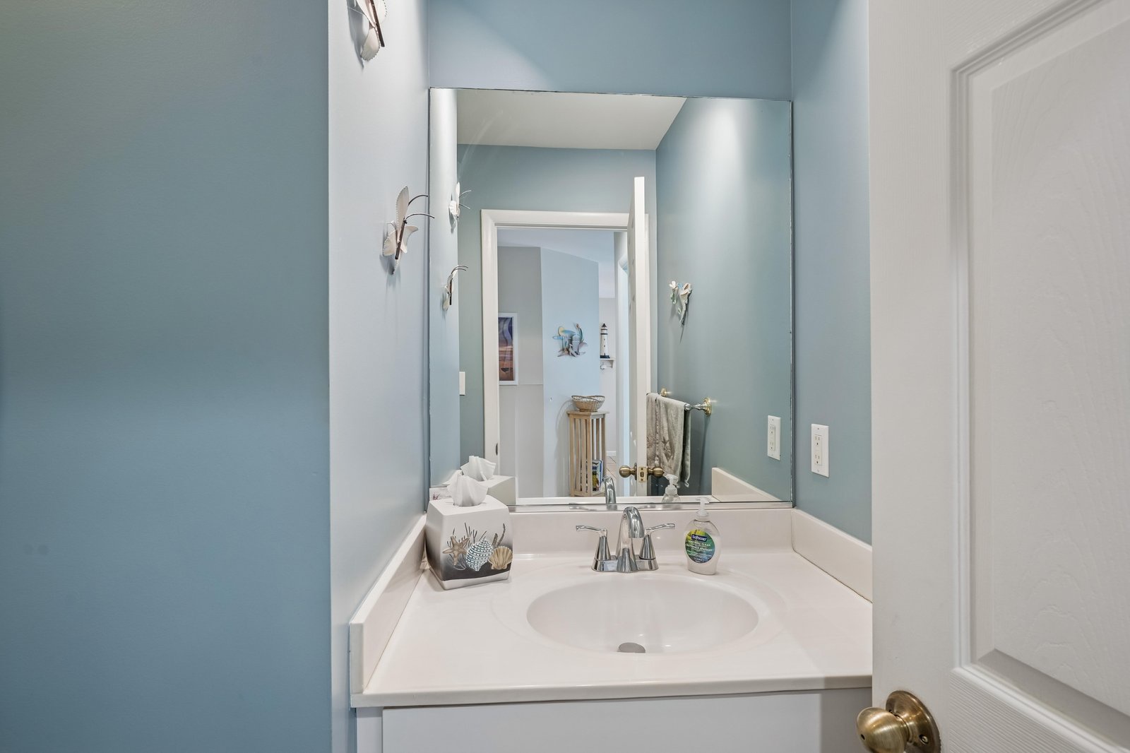 Your private bathroom features calming coastal blue tones, a well-lit vanity mirror, and soft white towels waiting for your arrival.