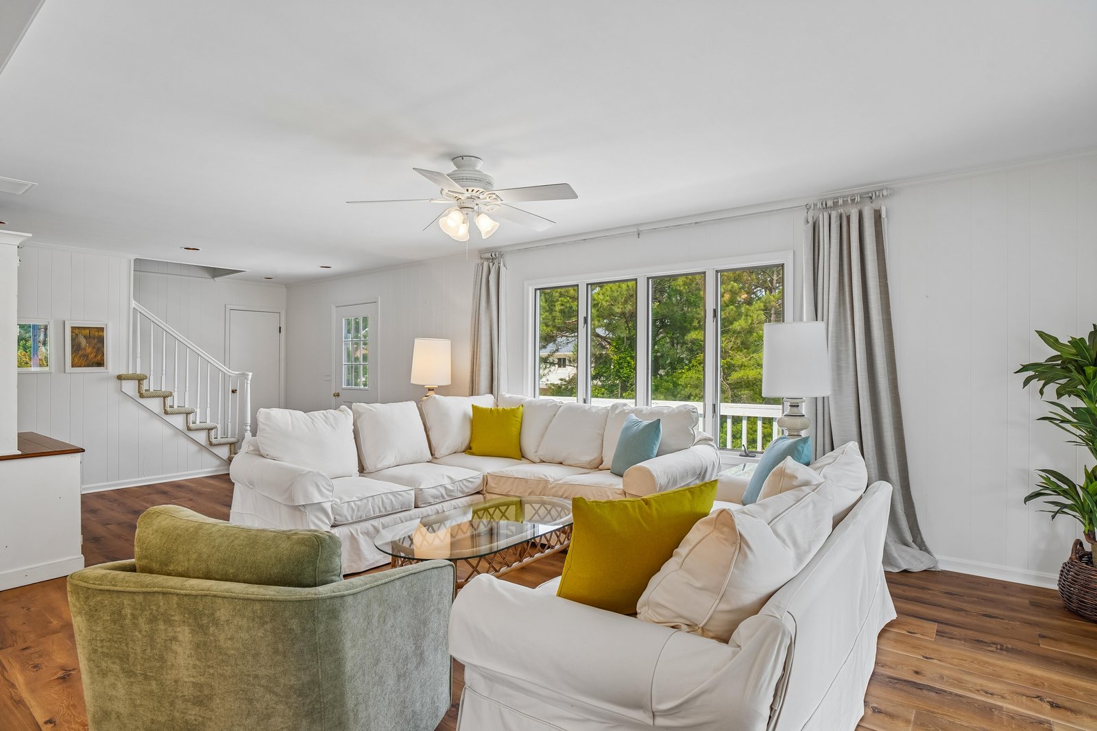 Sink into plush couches with pops of color and gaze through expansive windows to lush greenery beyond. The open layout and natural light create your perfect home base.