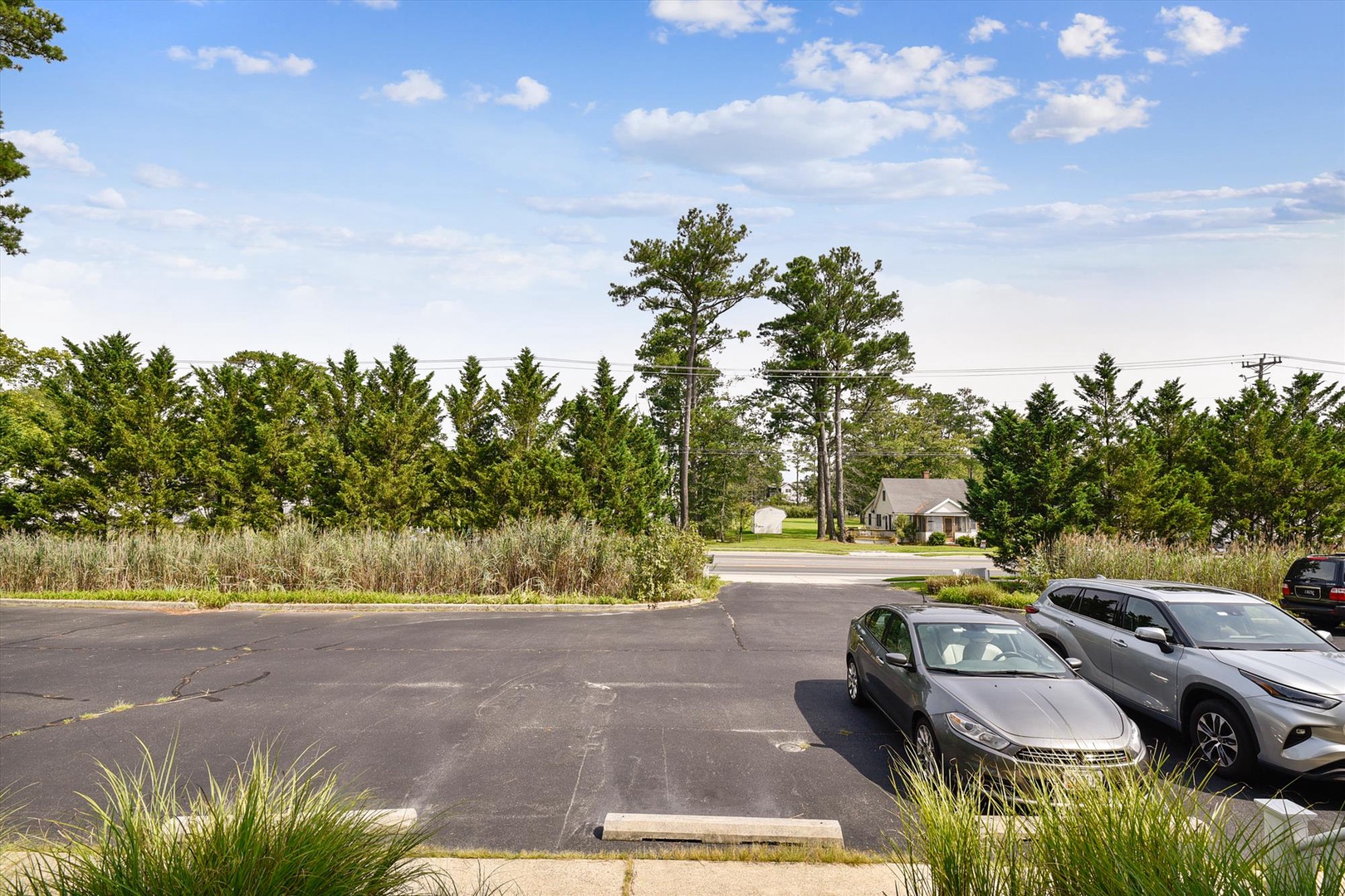Convenient parking area with easy access to the property, set amidst a quiet, tree-lined neighborhood with natural landscaping and open skies.