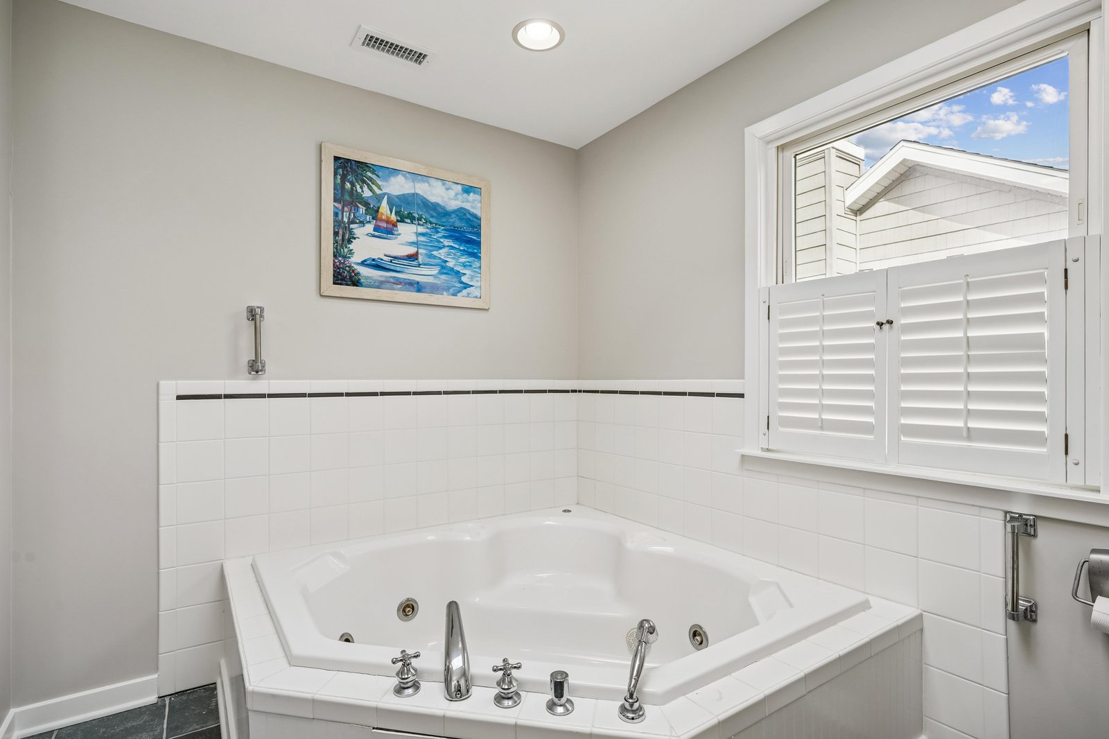 Soak away your cares in this elegant jetted tub, where coastal artwork and natural light create your personal spa retreat.