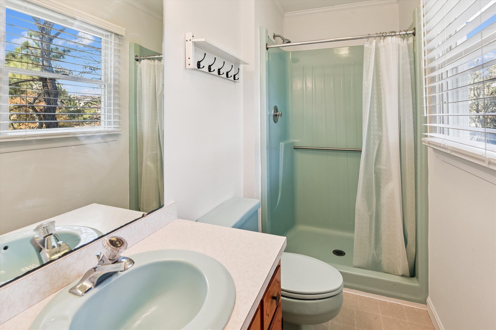 Step into your refreshing private bathroom featuring a spacious shower and bright windows that fill the space with natural light.