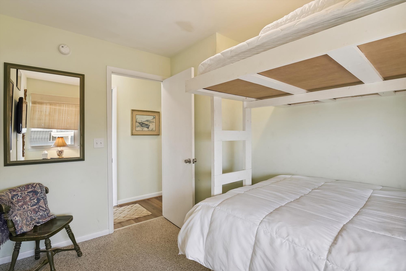 Drift off in your cozy bunk bed tucked beneath a charming lofted space, where white beams frame your peaceful retreat with warm, cottage-style comfort.