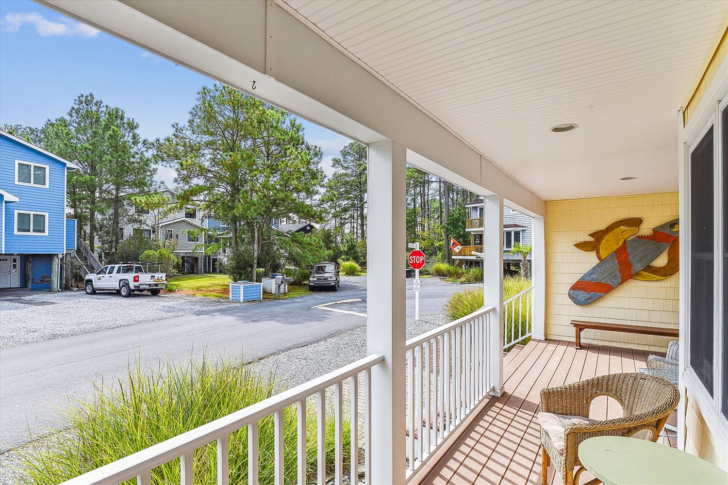 A welcoming covered porch with cozy seating overlooks the peaceful neighborhood, perfect for sipping morning coffee or unwinding after a day at the beach.
