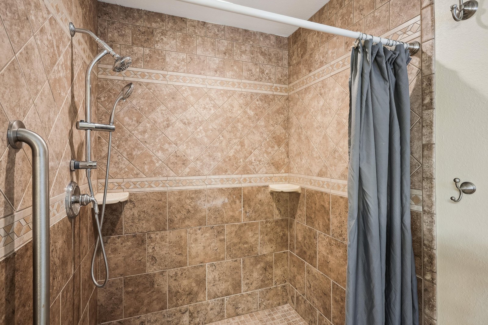 Your private shower features beautiful tile work, a handheld sprayer for comfort, and a convenient built-in seat for a relaxing rinse after a long day of exploring.