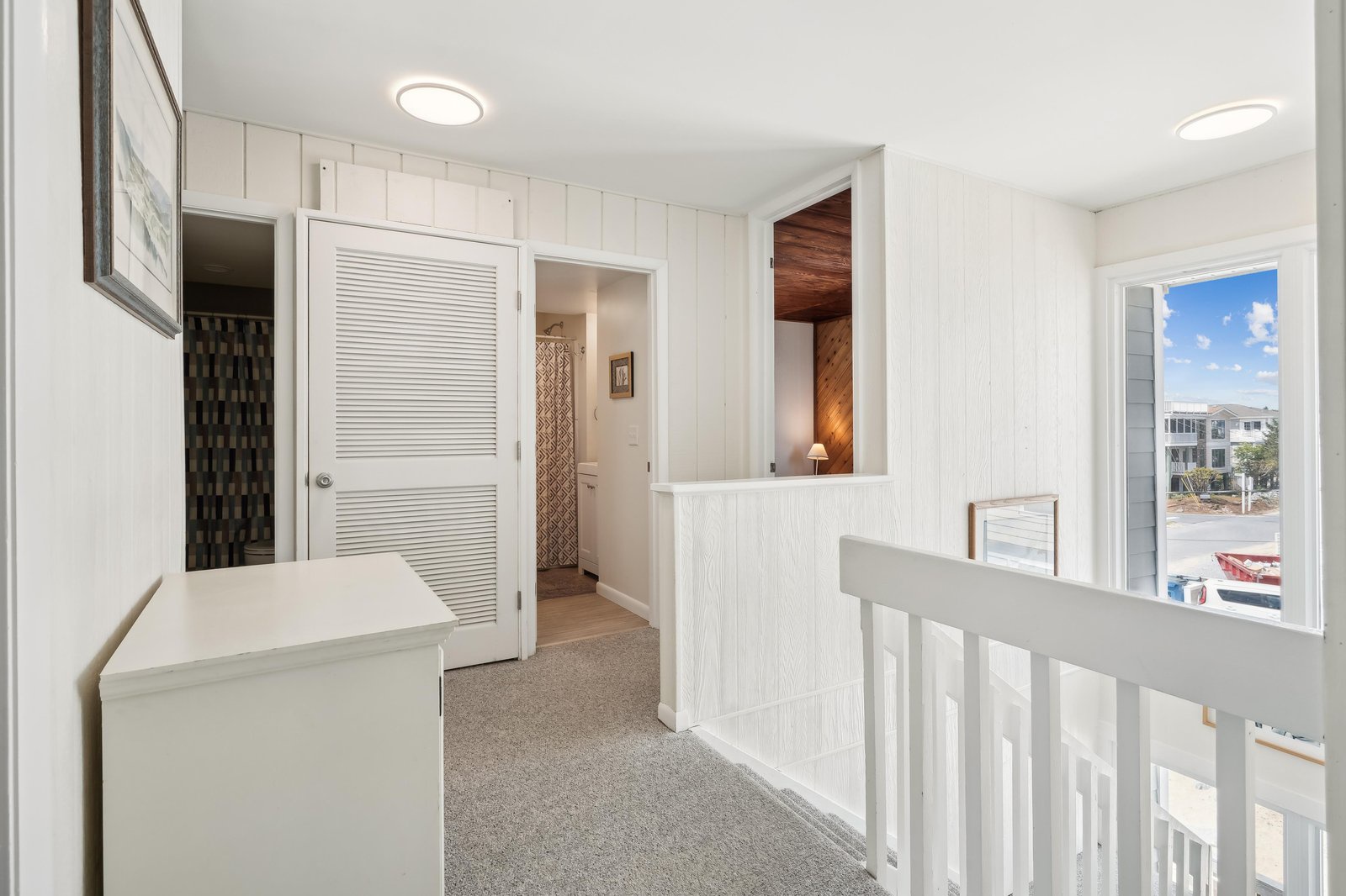 This bright hallway connects your private spaces with easy flow. Crisp white paneling, warm wood accents, and natural light from the windows create a welcoming retreat.