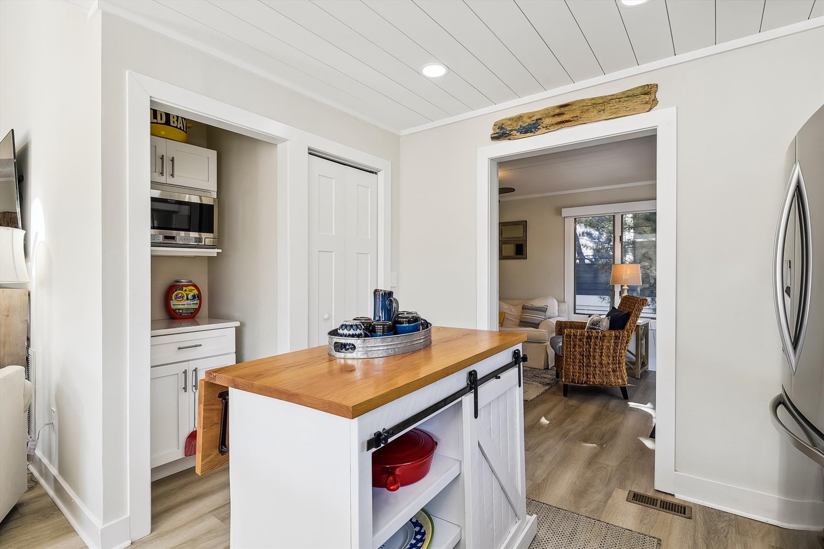 Your modern kitchen features a charming wood-top island with barn door storage, seamlessly connecting to a cozy seating area framed by natural light.