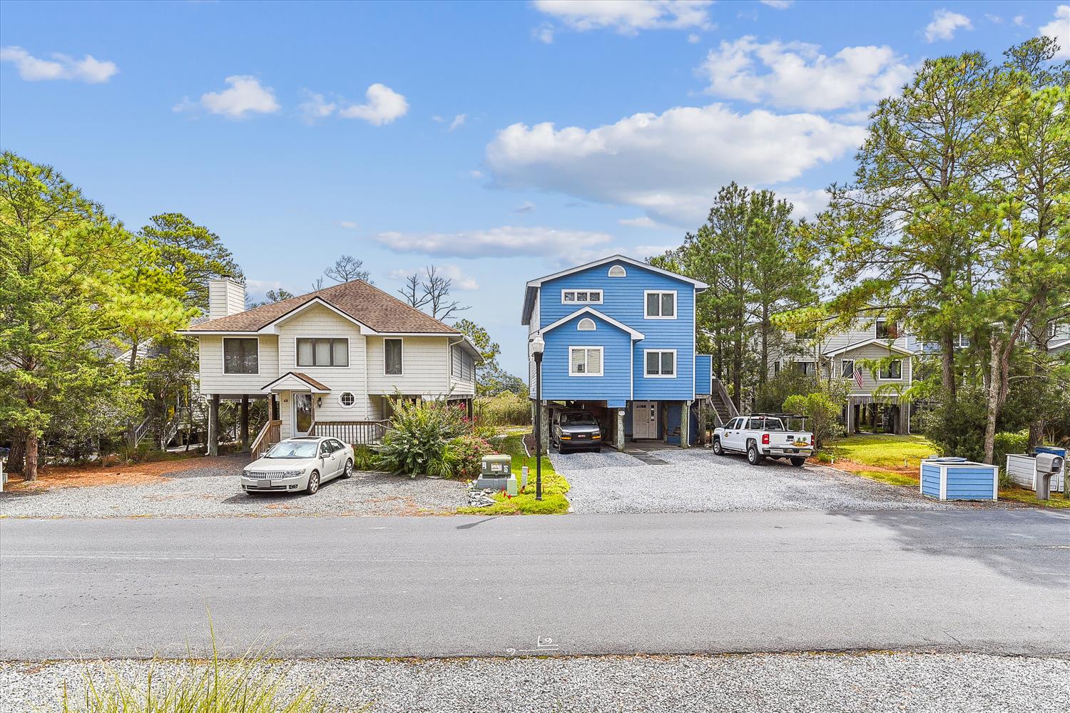 The property is nestled among tall pines and lush greenery in a peaceful residential setting, with convenient parking and nearby neighbors offering a welcoming neighborhood feel.