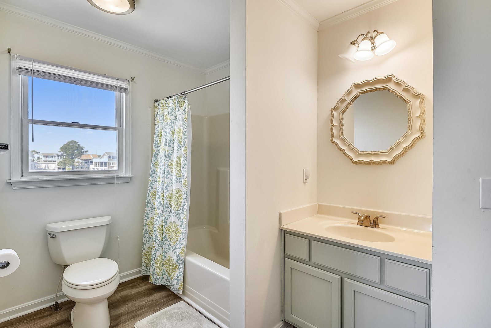 Your private bathroom offers a fresh, welcoming space with a tub, vanity, and elegant gold-framed mirror—perfect for unwinding after a day at the beach.