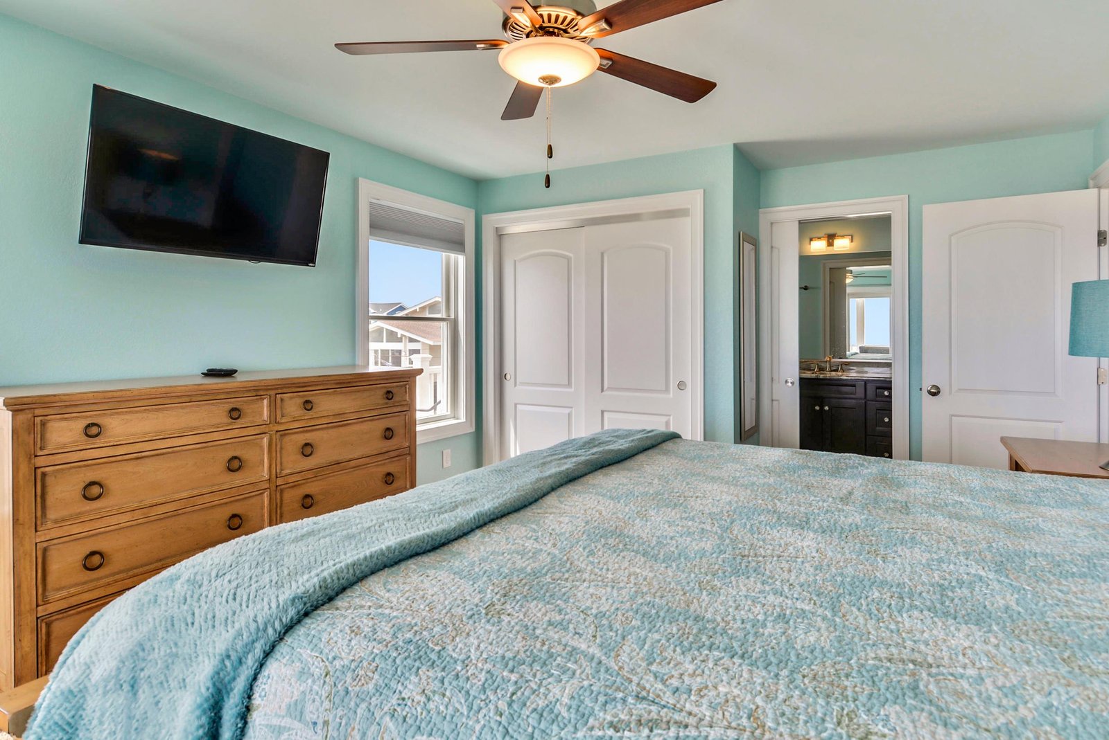 Drift off to sleep in soothing coastal hues, cooled by the gentle hum of the ceiling fan. Your dresser awaits, and the ensuite bathroom is just steps away.