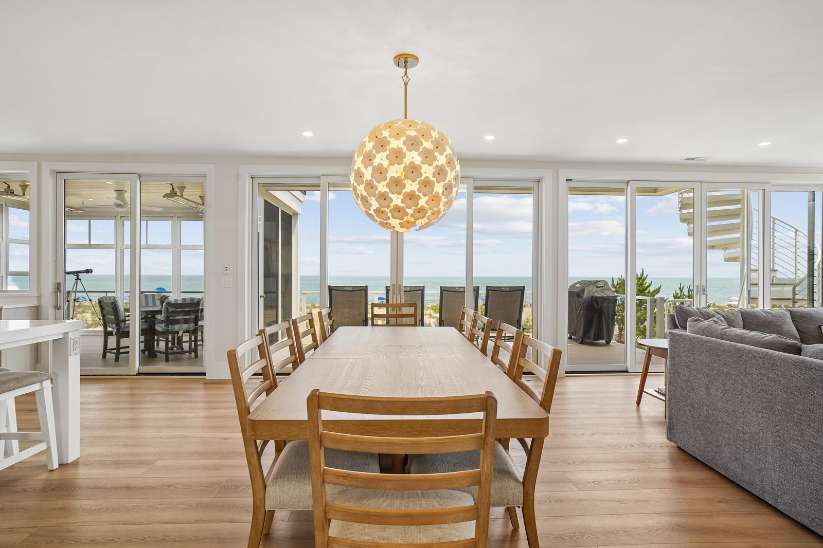 Picture yourself at this stunning dining table with sweeping ocean views through floor-to-ceiling windows. The warm wood tones and elegant chandelier create the perfect setting for memorable meals with loved ones.