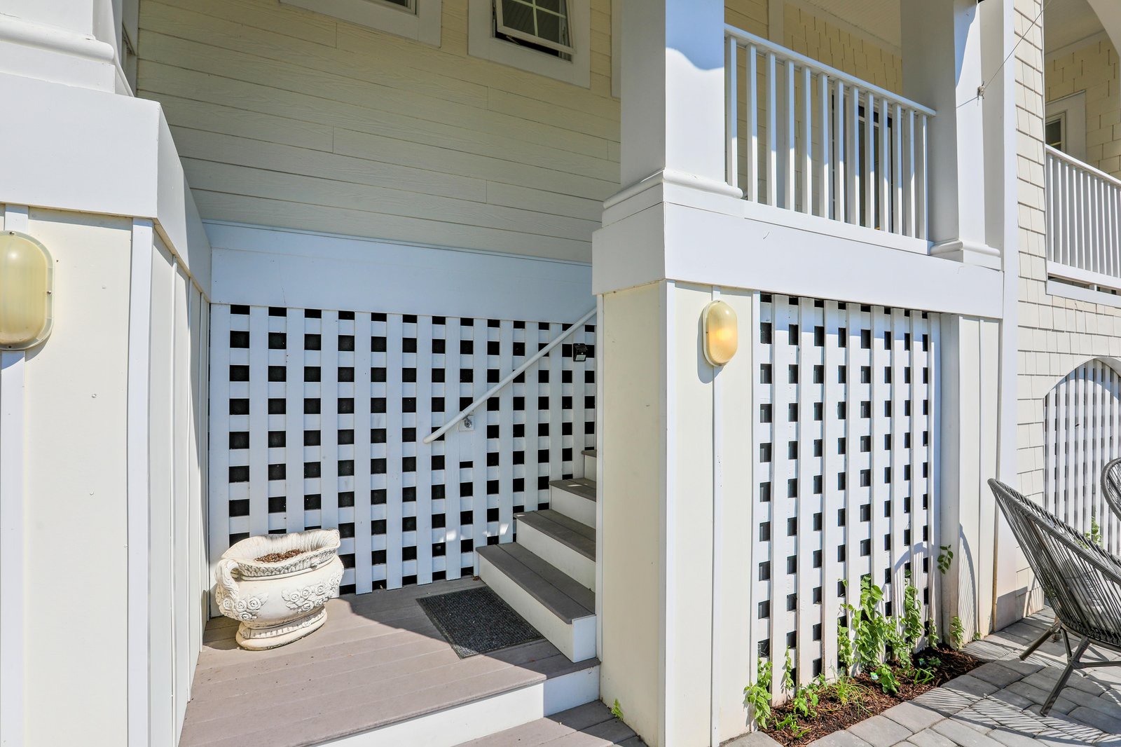 The lattice-trimmed entryway leads to your private outdoor space, complete with a charming decorative planter and cozy hammock chair.