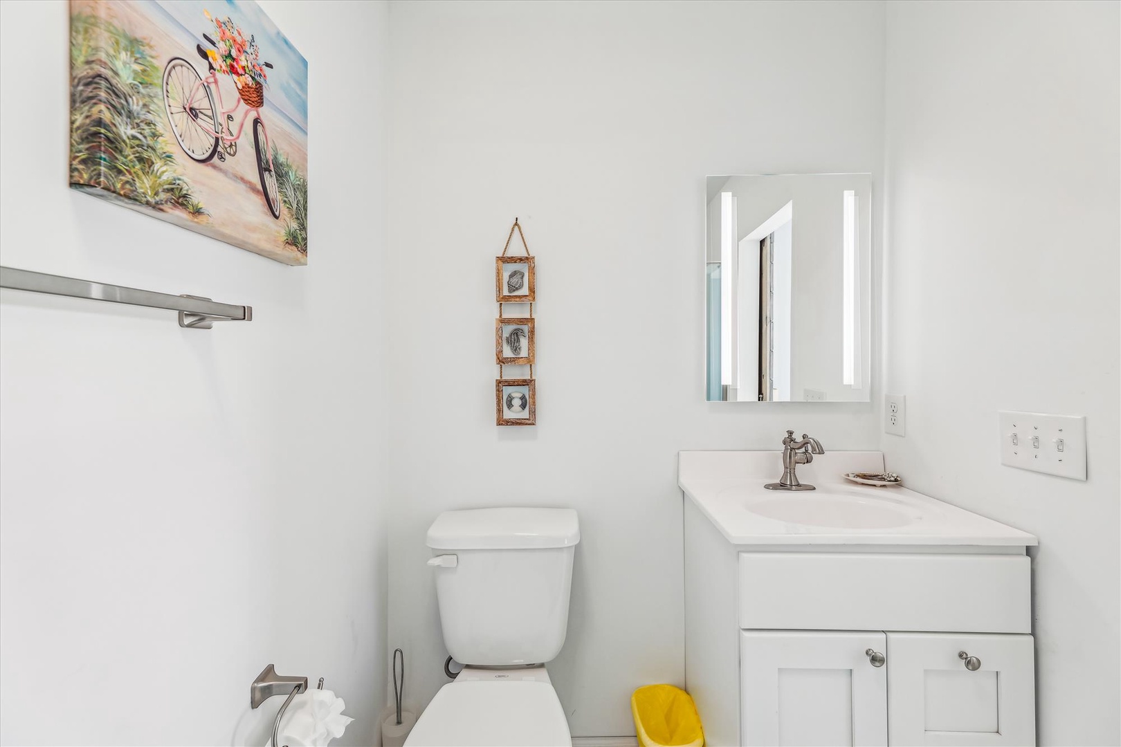 Freshen up in this crisp, coastal-themed bathroom with a bike painting to set the beachy tone. Your private sink and mirror are bathed in natural light for a bright, breezy start to your day.