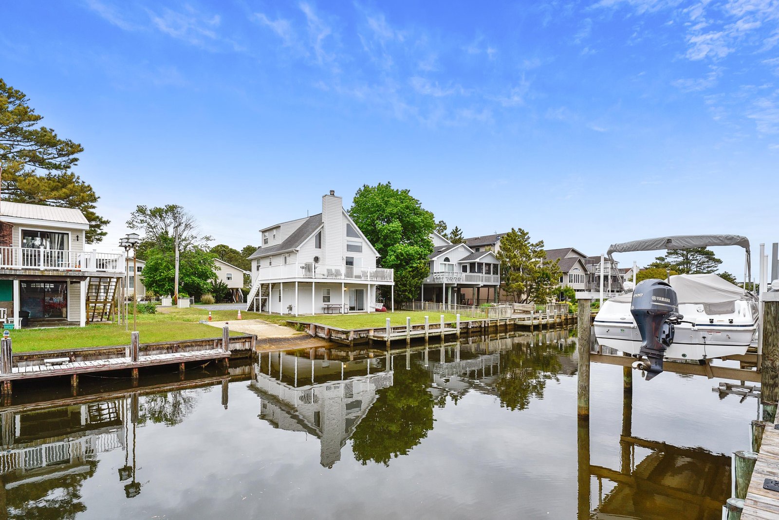 Waterfront homes line a peaceful canal where private docks and boat slips await your arrival, framed by lush trees and open skies.