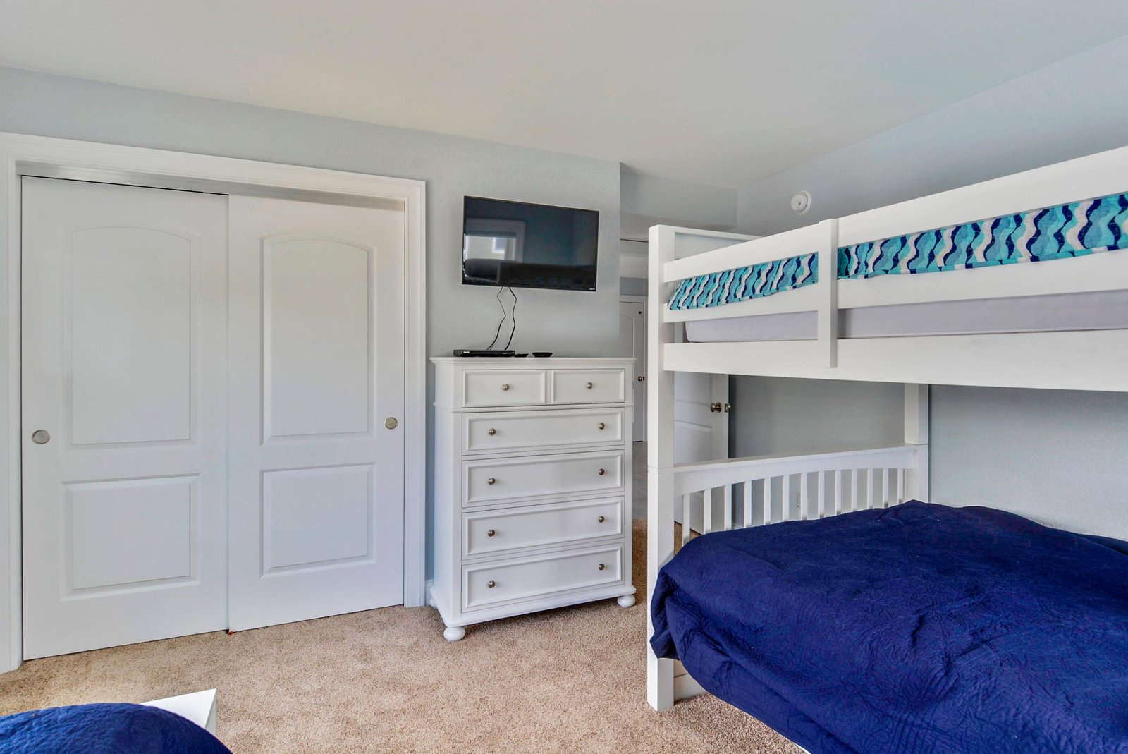 Your kids will love this cozy bunk room with crisp white furniture, plenty of storage, and a TV mounted right on the wall for their favorite shows.