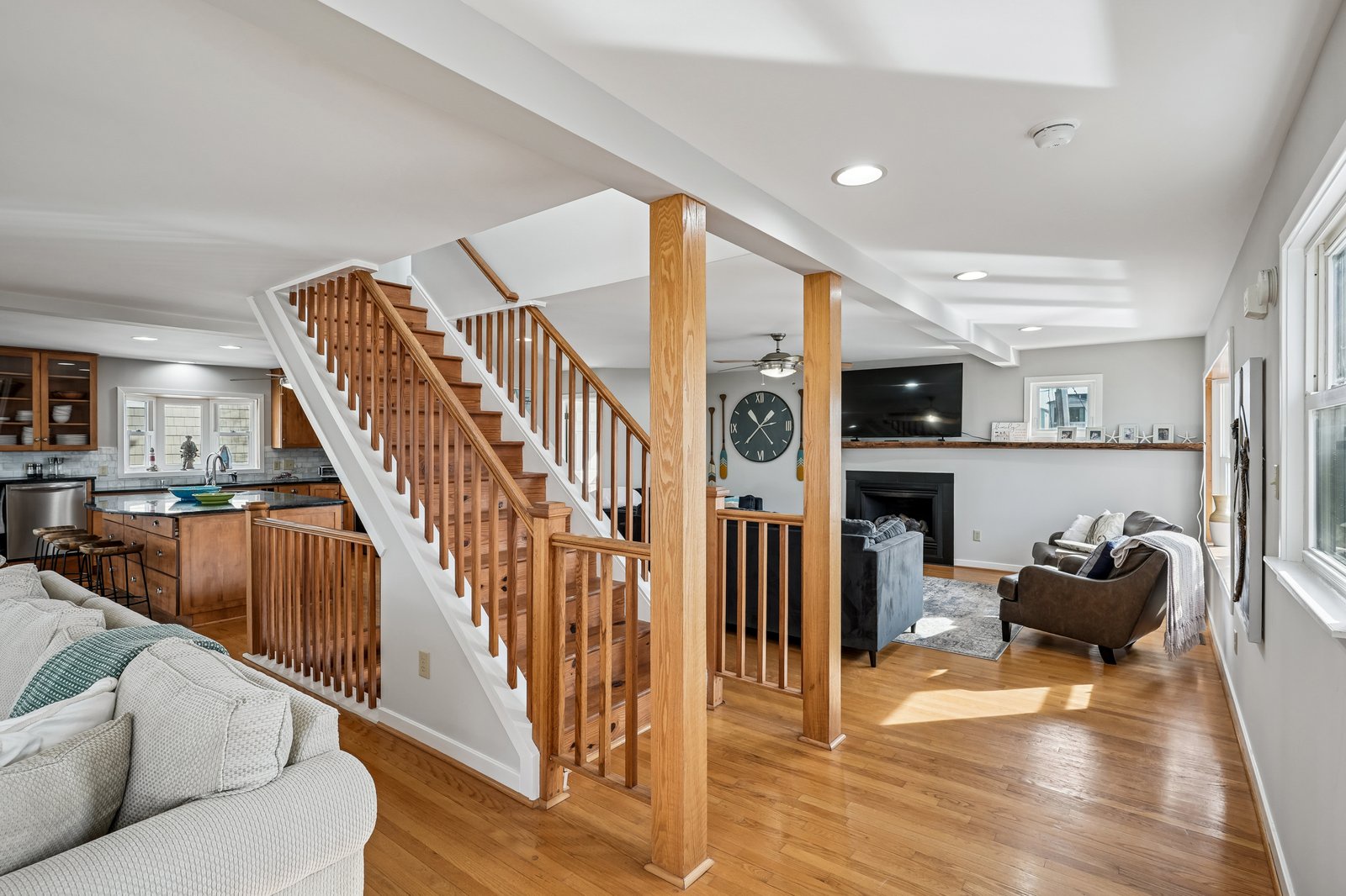 Relax in your spacious open-concept living area with gleaming hardwood floors, cozy fireplace, and warm natural light streaming through large windows.