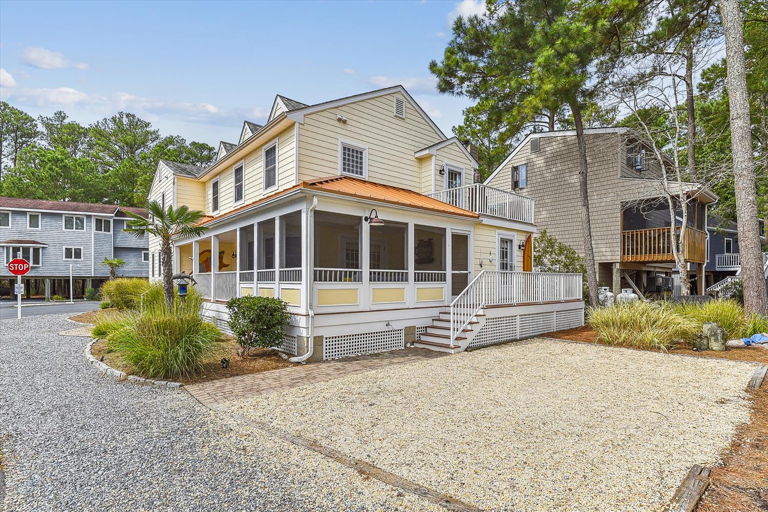 A coastal retreat nestled among tall pines, featuring a charming screened porch and landscaped grounds, located in a quiet neighborhood near the beach.