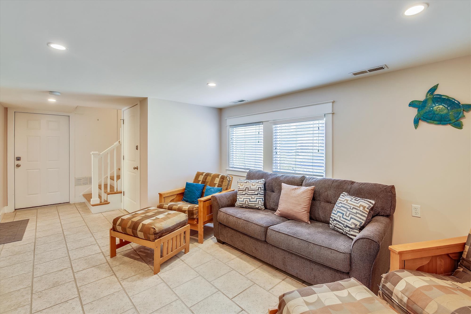 Sink into the plush sofa with coastal-themed pillows and let your worries melt away. Natural light fills this inviting living space, perfect for your relaxing escape.