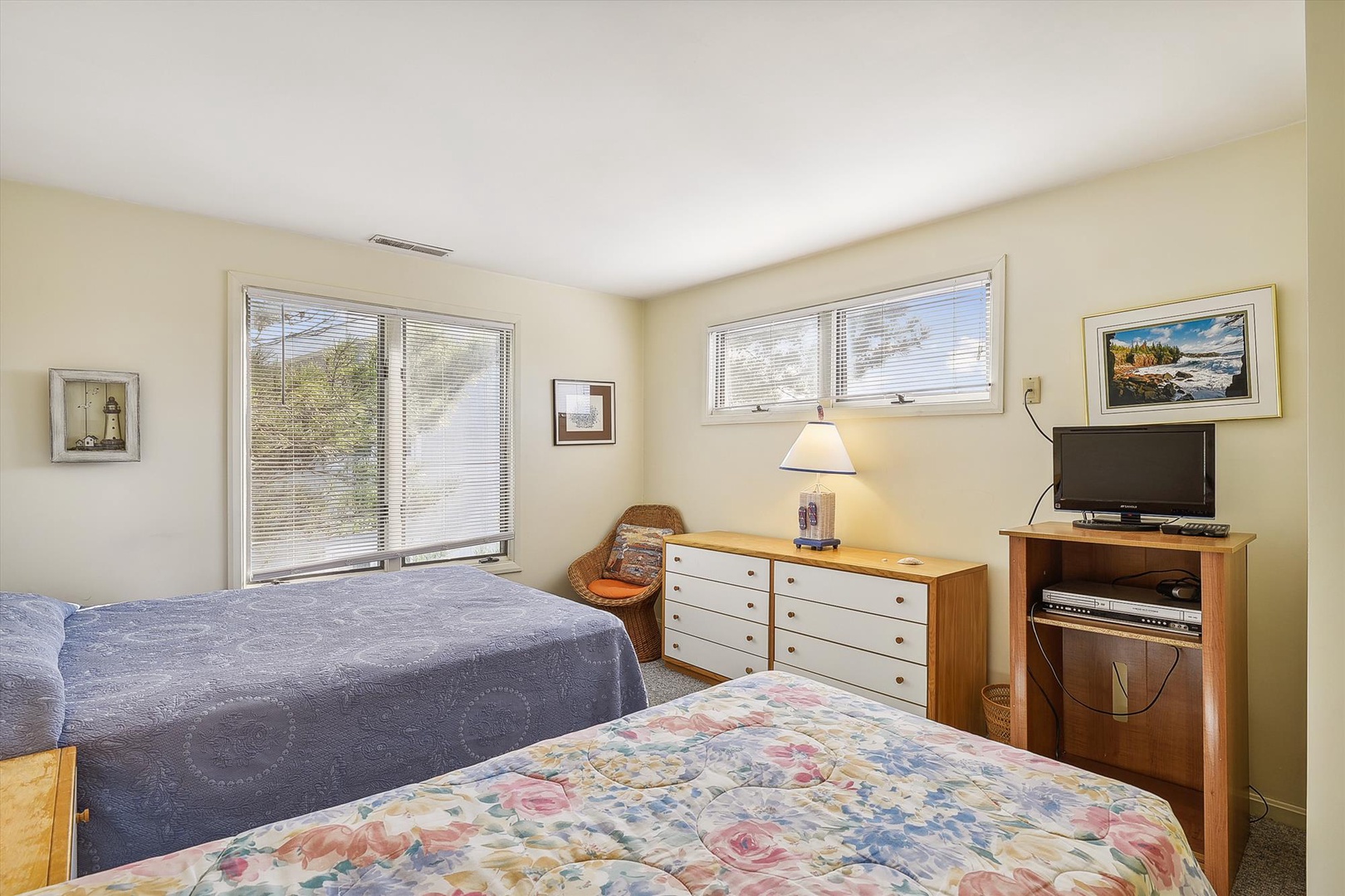 Relax in this bright bedroom with two cozy beds, natural light streaming through large windows, and your own TV for unwinding after a day of exploring.