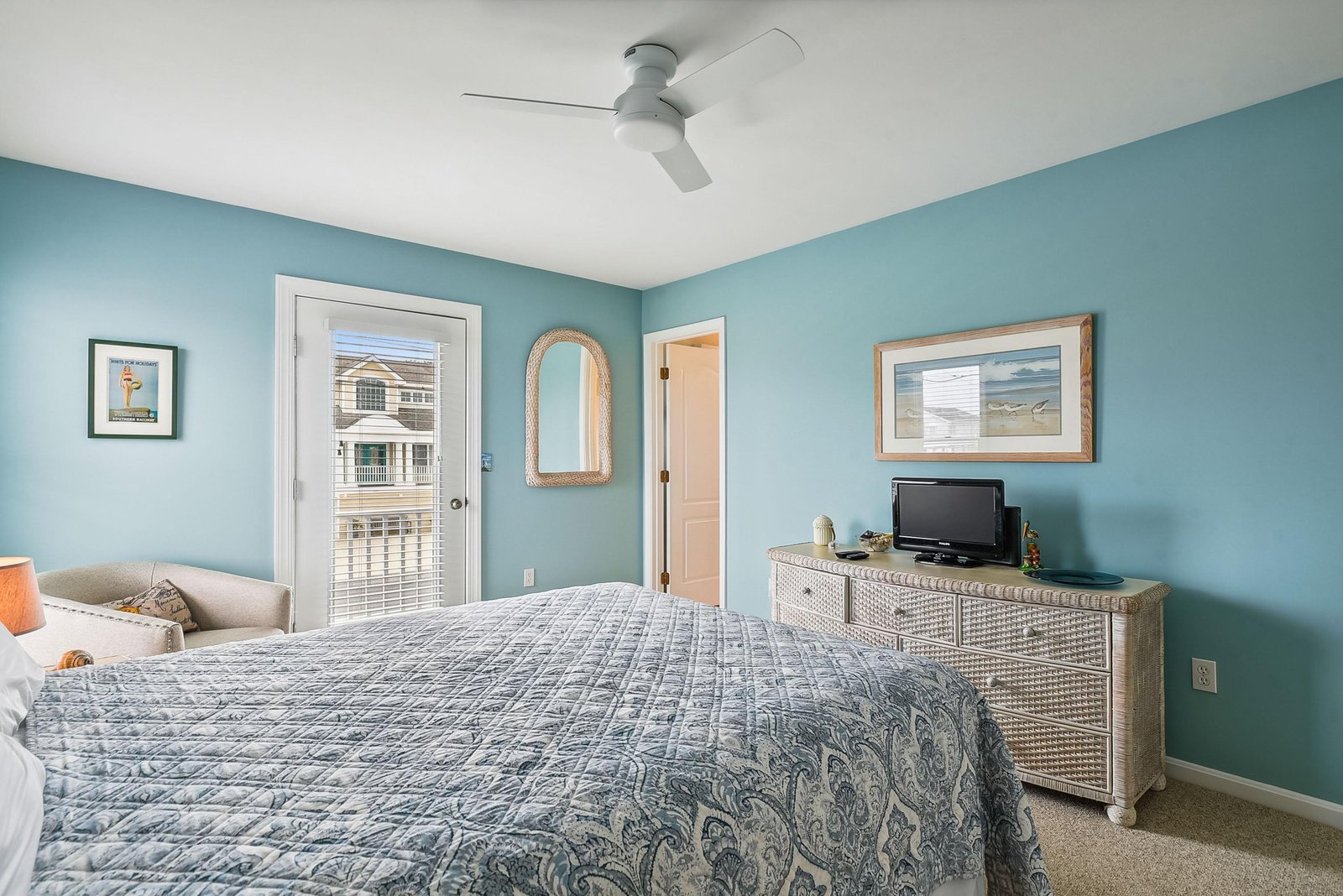 Unwind in this serene coastal-inspired bedroom, where soothing blue walls and a ceiling fan create your perfect retreat after a day of adventure.