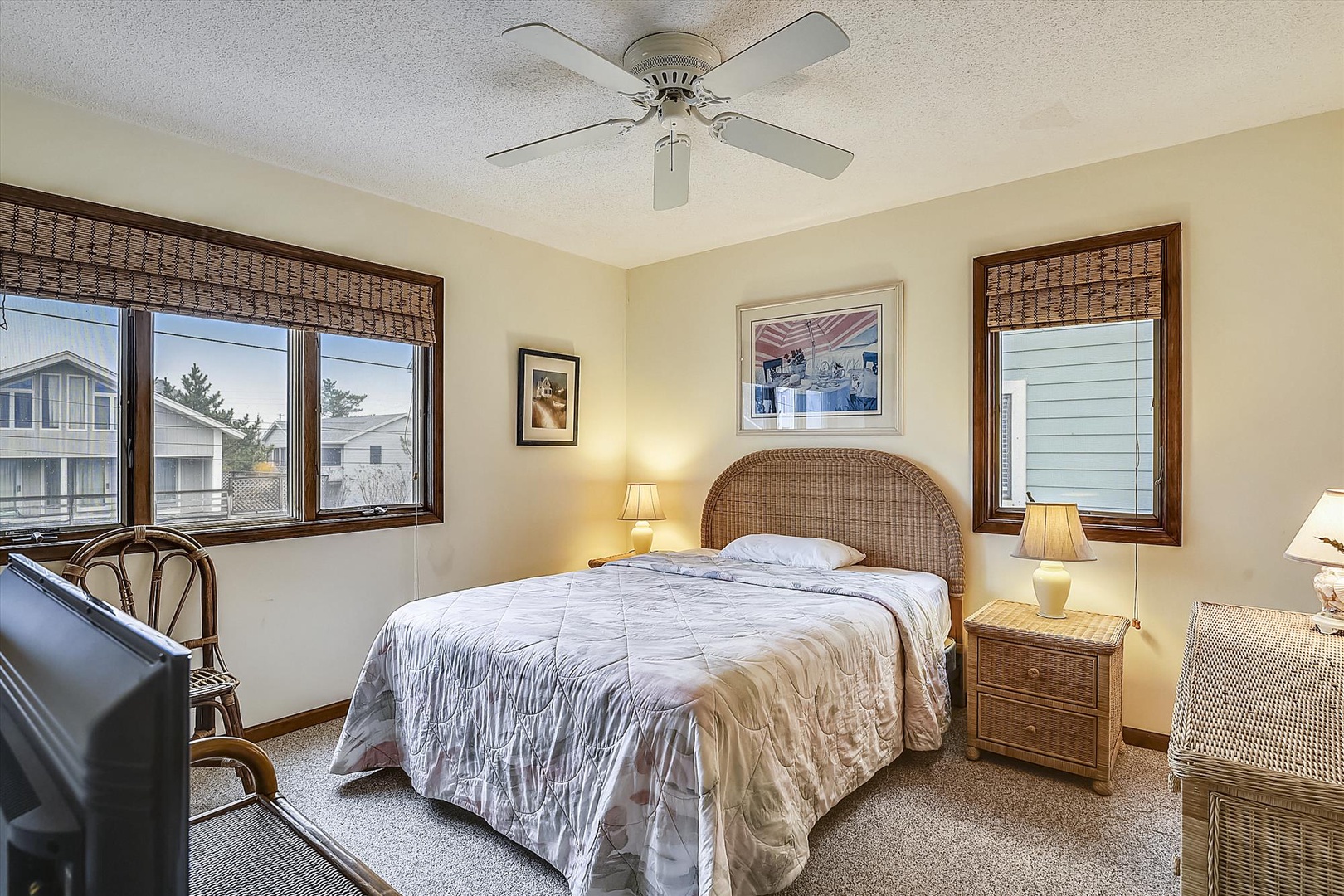 Rest peacefully in your cozy bedroom featuring coastal wicker furnishings, soft lighting, and bamboo window treatments that filter gentle natural light.