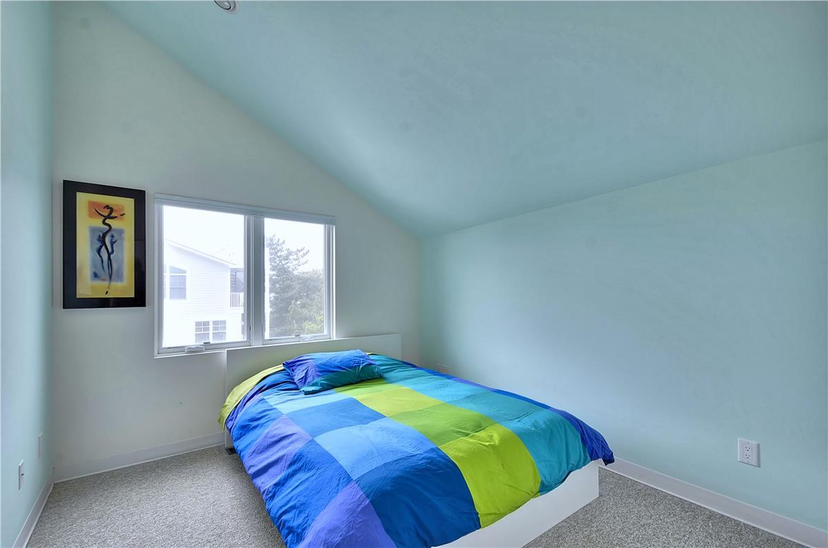 Rest easy in this peaceful bedroom, where soft coastal blues meet clean lines and natural light streaming through the windows. Your perfect escape awaits in this serene, uncluttered space.