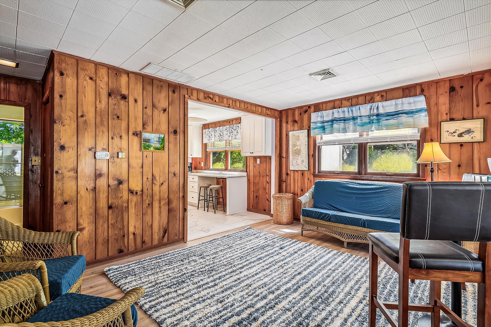 Your cozy living room welcomes you with rustic wood walls and comfortable seating where you can unwind after adventures, with the kitchen just steps away for easy snacking.