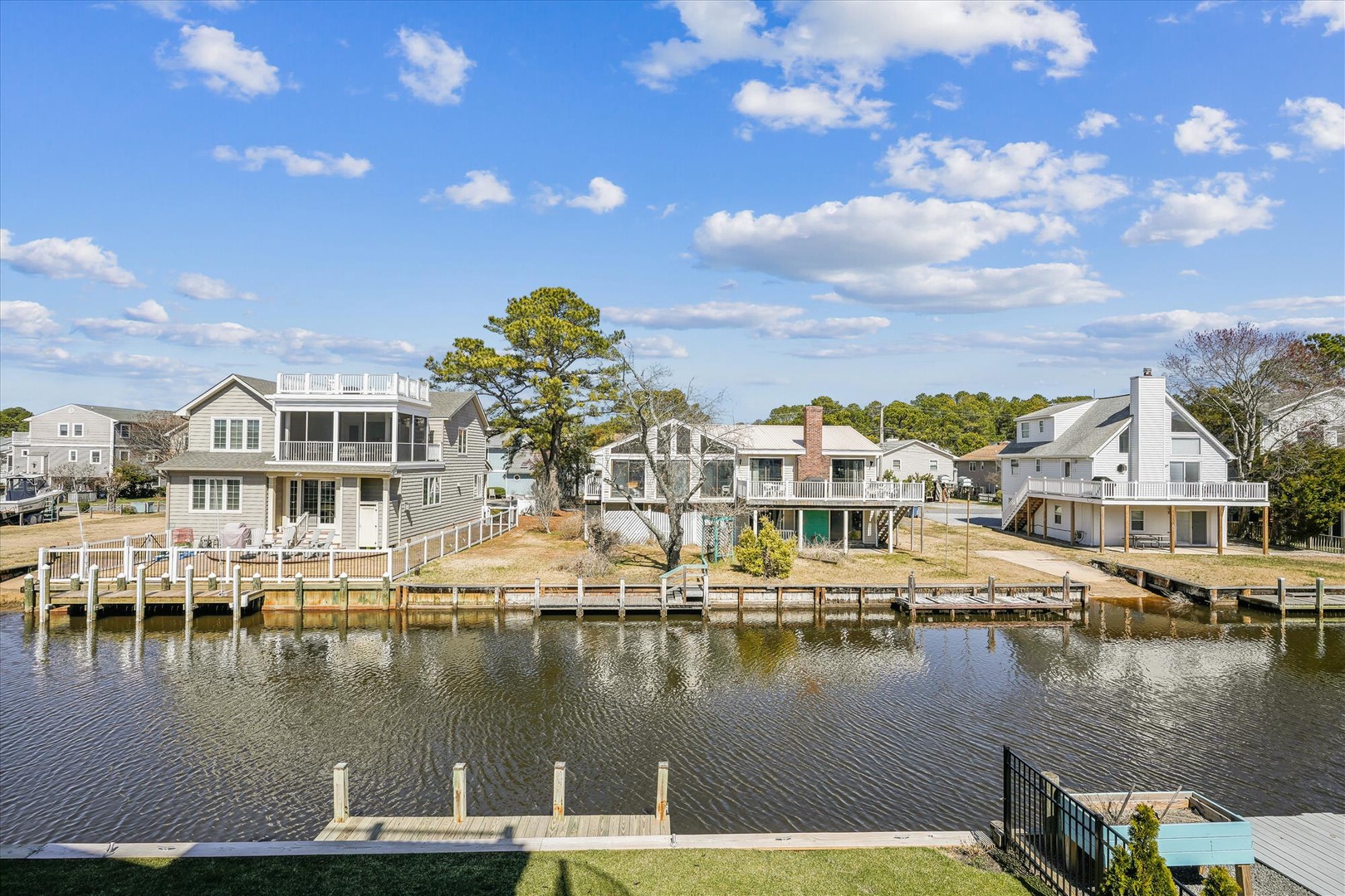 Waterfront community featuring charming coastal homes with private docks along peaceful canal waters under beautiful blue skies.