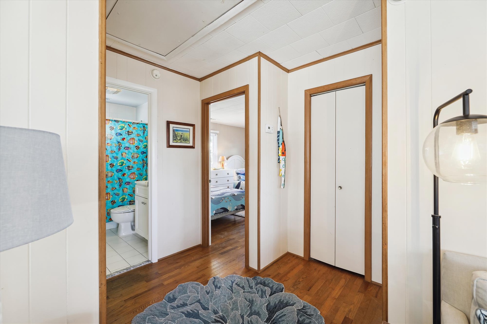 Your bright, well-organized hallway connects you to restful bedrooms and a charming bathroom, with warm wood accents and thoughtful lighting welcoming you home.