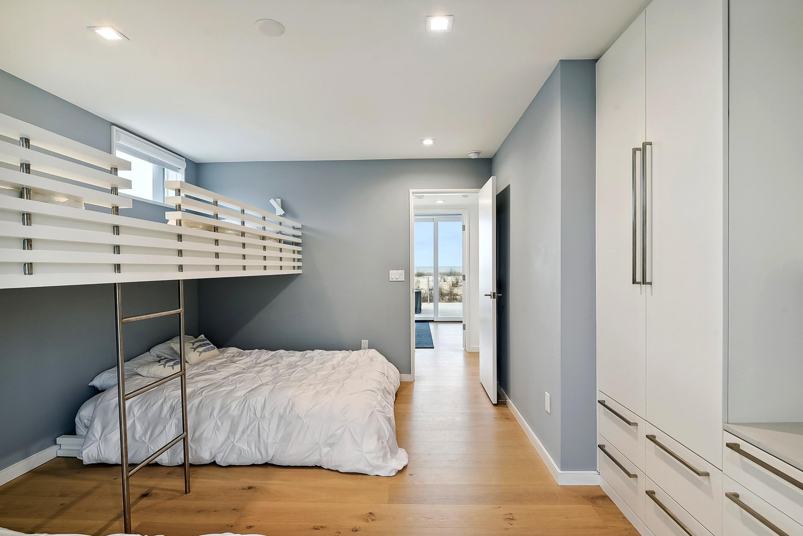 Your modern retreat features calming blue-gray walls, warm hardwood floors, and a bunk bed for the kids. Built-in storage keeps everything organized while you enjoy peaceful moments together.