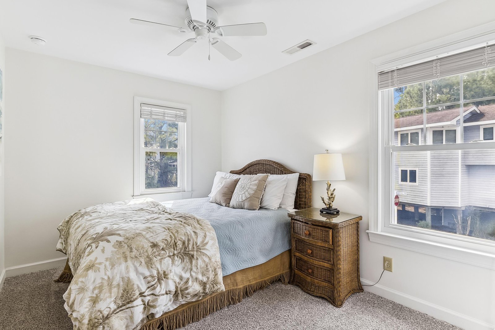 Light floods into your serene bedroom retreat, where soft neutral tones and coastal wicker accents create a peaceful haven for restful nights.