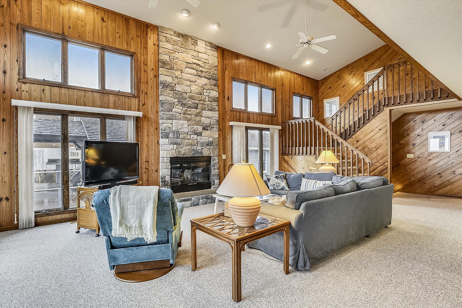 Unwind in your spacious living room featuring soaring vaulted ceilings, a cozy stone fireplace, and plenty of natural light. The comfortable seating and warm wood tones create the perfect retreat for relaxing after your mountain adventures.