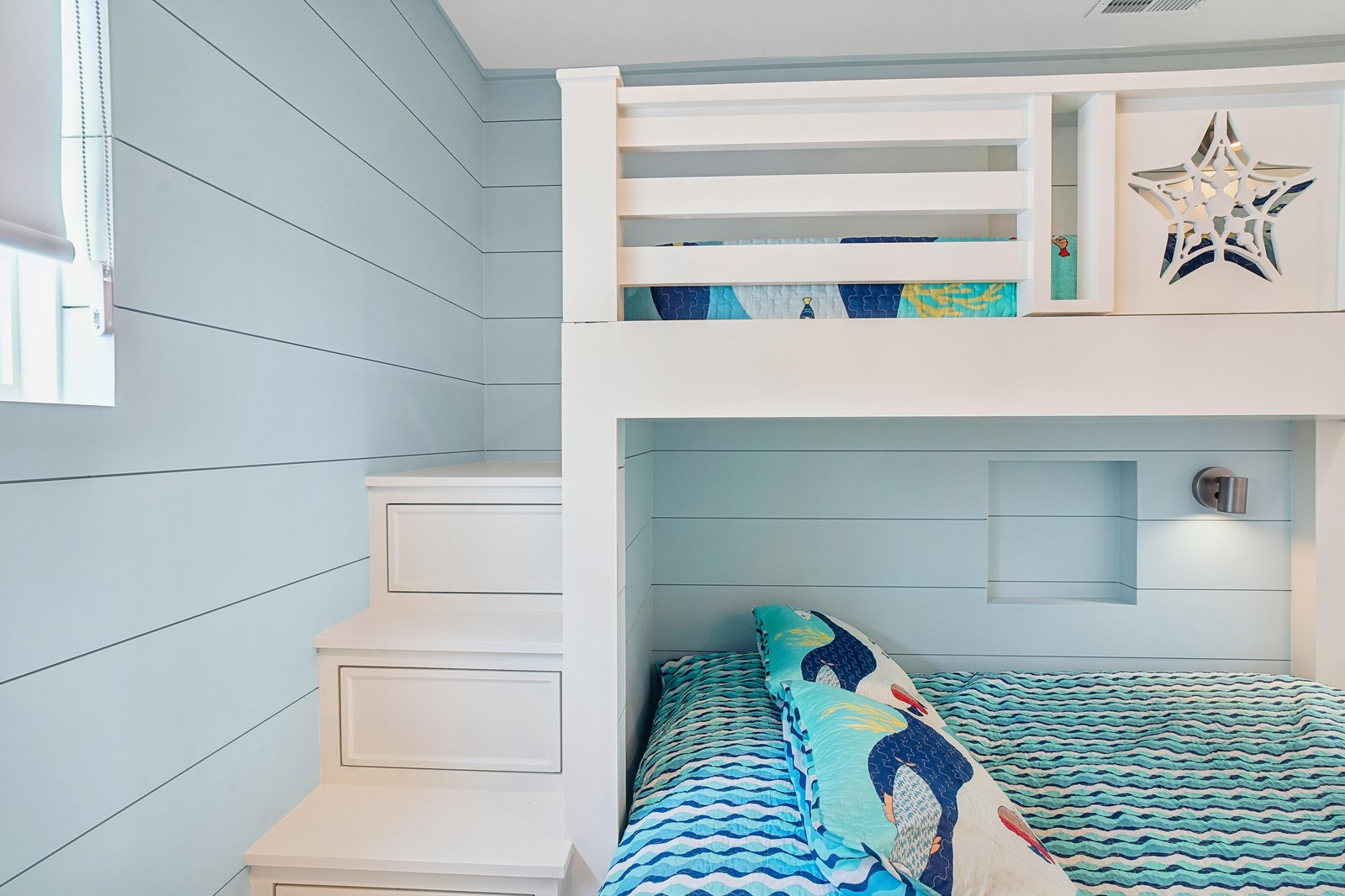 Rest easy in this charming coastal bedroom, where soft shiplap walls and cheerful ocean-themed bedding create a perfect seaside retreat for your little ones.